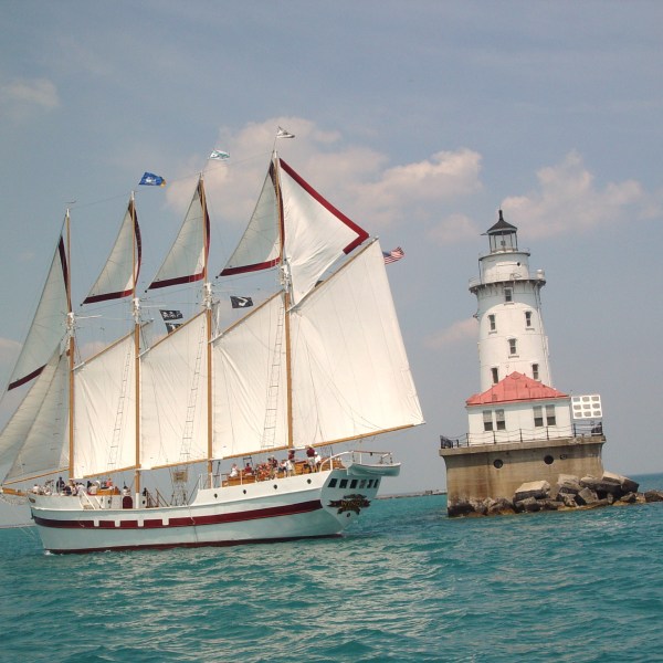 Tall Ship windy sailing past a lighthouse