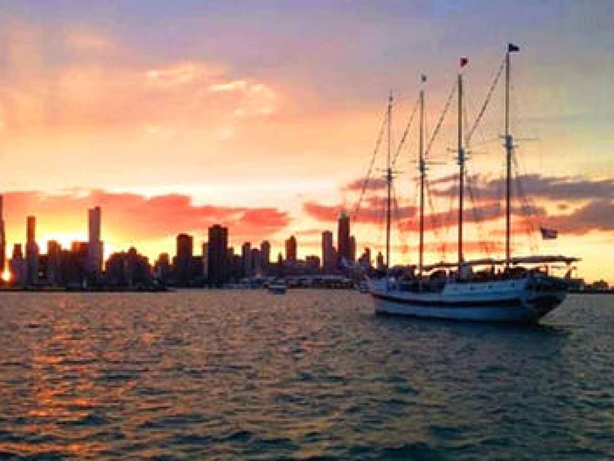 The Tall Ship Windy sailing toward the Chicago skyline at sunset