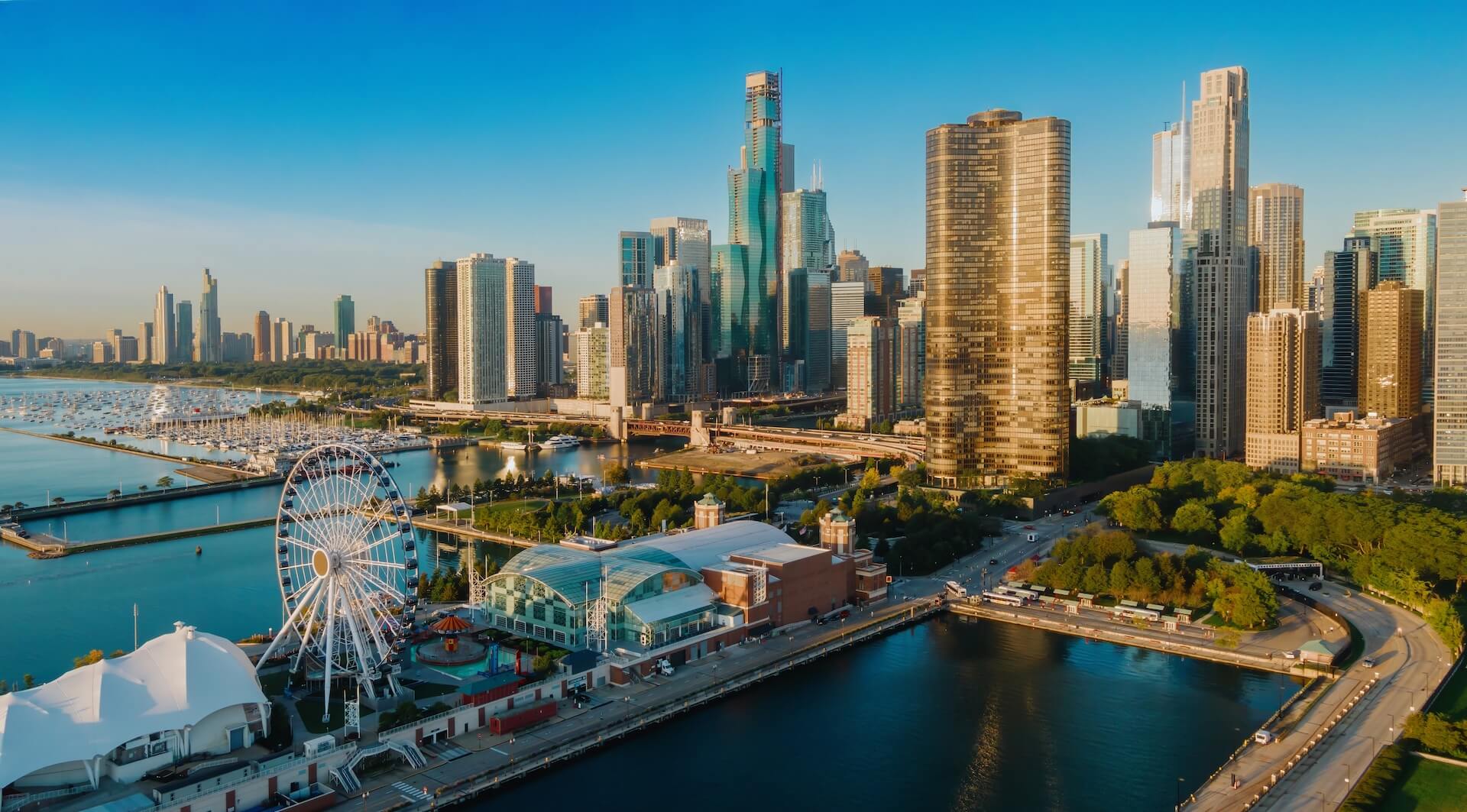 Aerial view of a city skyline with skyscrapers, a Ferris wheel, and waterfront park.